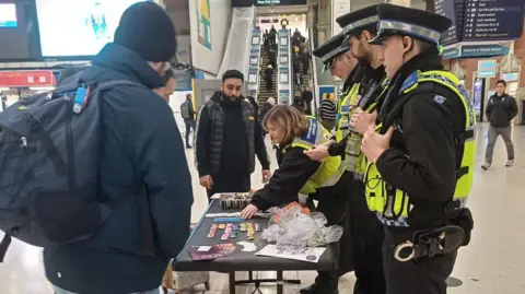 Govia Thameslink Four British Transport Police community officers operate a stall at Victoria Station in London, speaking to three members of the public about White Ribbon Day.