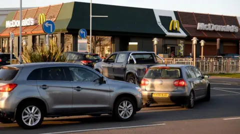 Getty Images Five cars line up at a McDonald's drive-through, waiting to make orders