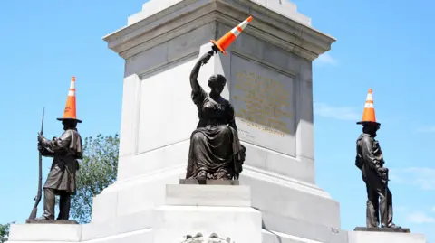 PA Media The Soldiers and Sailor Monument on Boston Common with the statues wearing orange and white traffic cones. 