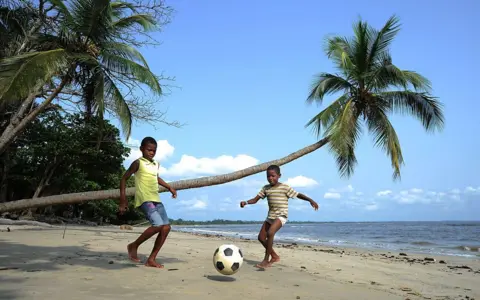 Getty Images Boys play football on a beach near Libreville in 2012.