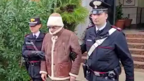 A screengrab taken from a video shows Matteo Messina Denaro the country's most wanted mafia boss being escorted out of a Carabinieri police station after he was arrested in Palermo, Italy, January 16, 2023.