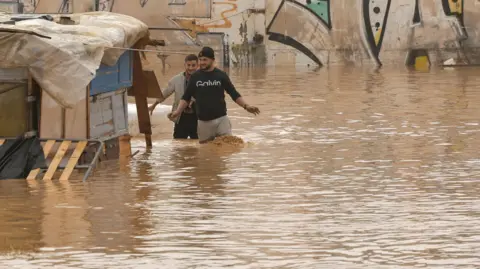 EPA people walk across a flooded highway in the city of Valencia