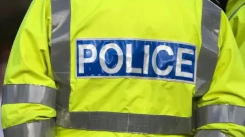 Getty Images The back of a police officer's uniform. It is yellow in colour and reads 'Police'.