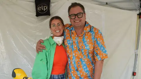 Interior Design Masters/BBC One Roisin Quinn is standing next to Alan Carr on the set of the BBC show Interior Design Masters.