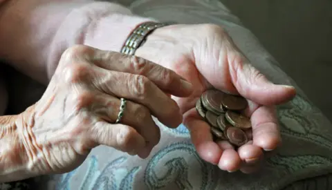 PA Media Elderly lady's hands counting out loose change