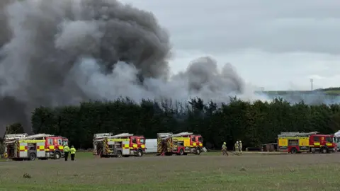 Nottinghamshire Fire and Rescue Service Smoke rising behind trees with fire engines in attendance