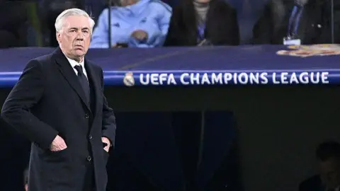 Carlo Ancelotti stands next to a Champions League sign