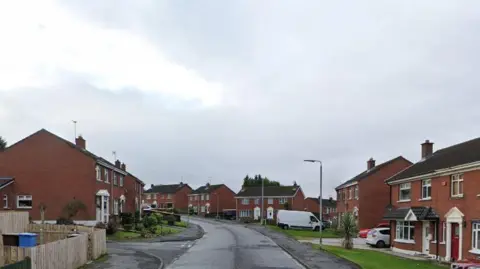 A road with red brick houses on each side. 