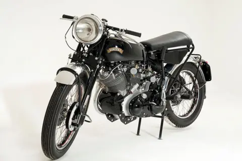 Getty Images A black motorbike with small handles and a large headlight sits in an all white room