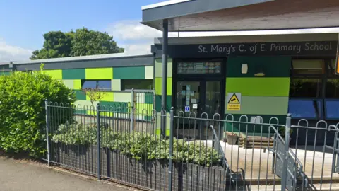 The outside of a school building with the sign - St Mary's Church of England School. 