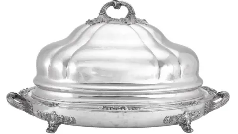 An Indian Silver Venison-Dish and Cover by Hamilton & Co. of Calcutta. The dish is large with ornamental flourishes at its base and sides.