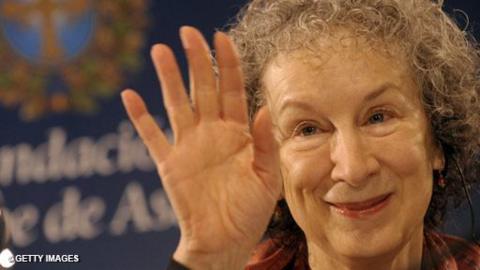 Writer Margaret Atwood holds up her hand in a wave.