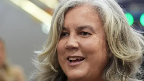 Ian West/PA Wire A woman with long grey hair smiles at someone off camera.