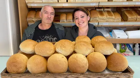 Andy and Emma Godfrey standing behind a large collection of bread rolls