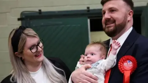 PA Media Chris Webb and wife Portia with baby Cillian at the count of the Blackpool South by-election in 2024