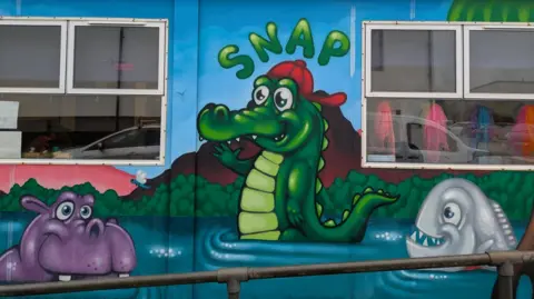 Cindy Jenkins A colourful animal-themed mural painted on the outside of SNAP Specialist Play's centre, with the unit name 'SNAP' painted in the centre.