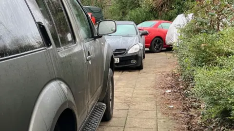 A pavement blocked by cars in Stockport.