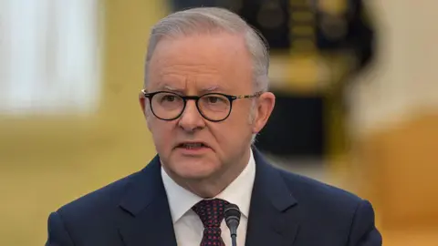Anthony Albanese wearing a navy suit and red and navy tie