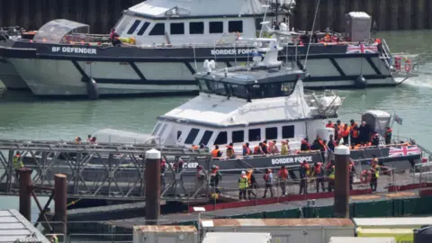 PA Media Um grupo de pessoas que se pensa ser migrantes são trazidas para o complexo da força de fronteira em Dover, Kent, de dois vasos de força de fronteira após um pequeno incidente no canal.