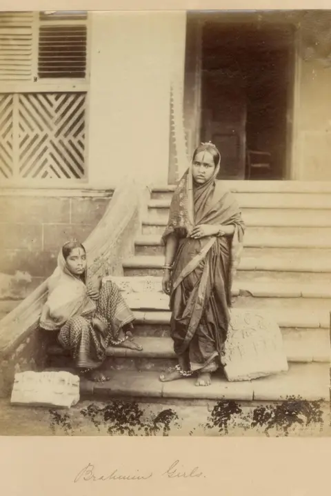 DAG Two high caste Hindu women in traditional saris pose on the steps of a house in Bombay in 1855 