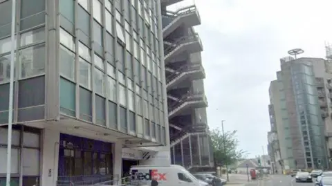 tower block with cars and vans parked outside