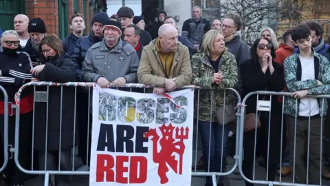 Reuters Stone Roses and Manchester United outside the cathedral service with a sign saying "Roses are Red"