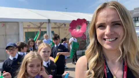 Andrew Turner/BBC Teacher Roni Longman with a giant flower and children from Ormiston Herman Academy at a workshop session for the Out There Festival