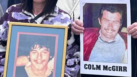 Cropped image showing framed photographs of two dark haired men- Colm McGirr and Brian Campbell, held up outside court