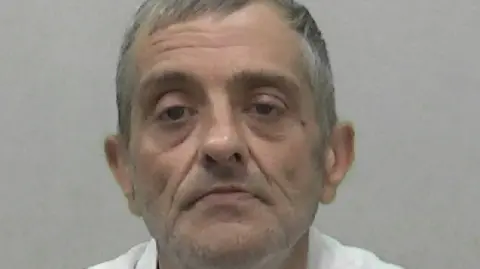 Mugshot of Alistair Paylor. He has short grey hair and wears a white shirt.