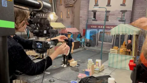 Number Nine PR An animator moves two of the puppets in a small market scene.