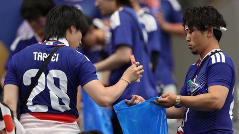 Japanese fans cleaning a stadium