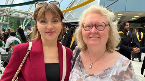 Two women smiling at a graduation ceremony