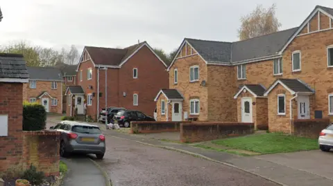 Google A general view of Geoff Seaden Close in Colchester. It is a narrow residential road lined with cream brick houses.
