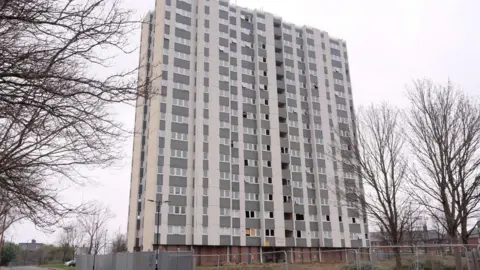 The derelict Hexham House. The building is 16-storeys tall and surrounded by chain fences. Many of its windows have been smashed.