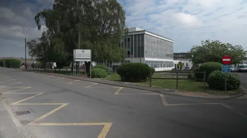 Exterior of the University Academy Long Sutton school a three-storey modern building with large glass windows surrounded by grass with the school sign facing the road