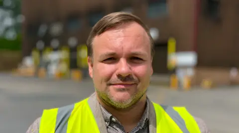 Martin Giles/BBC A head and shoulders image of MP Terry Jermy, who is wearing a hi-vis over a shirt. He is looking directly into the camera.