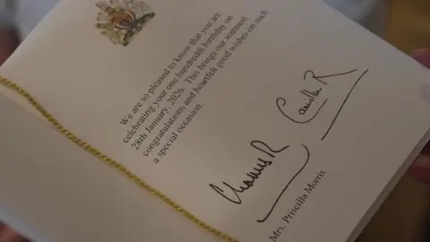 A close up of the card from the Royal couple which they have signed, and in which they wish Cilla their "warmest congratulations and heartfelt good wishes".