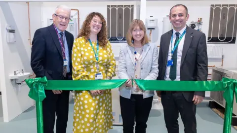 Wiltshire College & University Centre Four adults stand together, with MP Sarah Gibson cutting a green ribbon to open a new training facility.