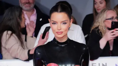 PA Media Maura Higgins wearing black PVC top with her hair up. 