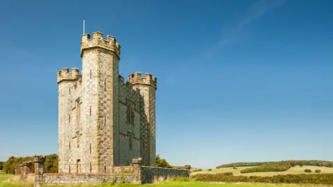 Getty Images The image shows a triangular castle on a field, with a blue sky to frame it.