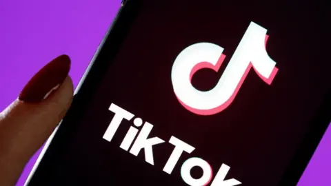 Getty Images File photo of a hand holding a phone with the TikTok logo