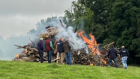 Several farmers surround a lit bonfire at Shadog Farm in Ceredigion