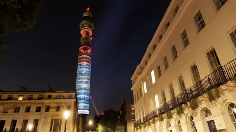 University of Reading The blue-to-red gradient projected sideways onto a tall thin tower at night, with buildings lit by streetlamps in the foreground