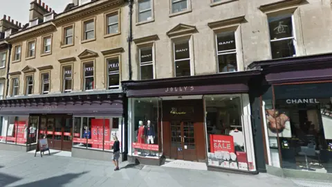 An exterior view of Jolly's department store, with "Sale" notices in the window