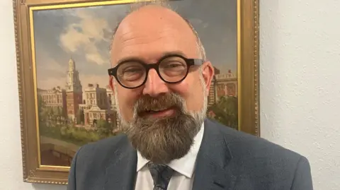 Richard Stead/BBC A man with circular black glasses and a bald head and beard. 