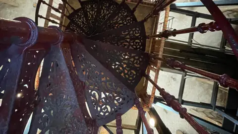 Laura Foster/BBC A downward view of a spiralling metal staircase inside the water tower