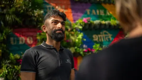 Landscape artist and architect Shiraaz Ali at the Living Wall of Peace next to Laisterdyke Library