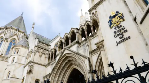 Exterior view of the Royal Courts of Justice in London, showing the Gothic stone facade and main arched entrance.