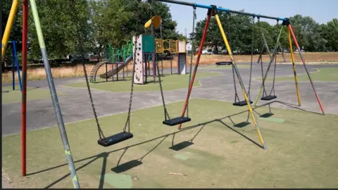 Danny Lawson/PA An image of a child's play area. There are swings in the foreground and a slide and climbing frame to the rear