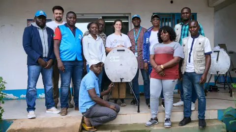 The Washing Machine Project A group of mainly Congolese people pose around a manual washing machine.